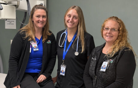 Three medical professionals smiling in a clinic.